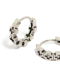 Crafted from waterproof brushed stainless steel with multiple cross details, these mens huggie hoop earrings in silver and black close up view - link has visual effect only