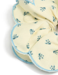Crafted from fabric with daisy print, this cream blue ruffled scrunchie in ivory, sky blue and teal detail view - link has visual effect only