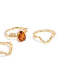Crafted from gold plated metal, this 3-pack of statement rings features red teardrop cubic zirconia and wavy crystal band designs side detail view - link has visual effect only