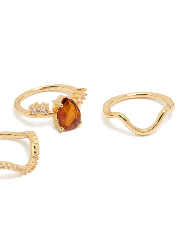 Crafted from gold plated metal, this 3-pack of statement rings features red teardrop cubic zirconia and wavy crystal band designs side detail view