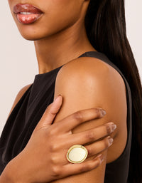 Featuring a gold plated ring with oval cream stone in ivory on finger view - link has visual effect only
