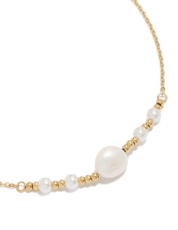 Showcasing a waterproof statement necklace crafted from stainless steel with beads and pearl accents in gold plated and white tones close up view