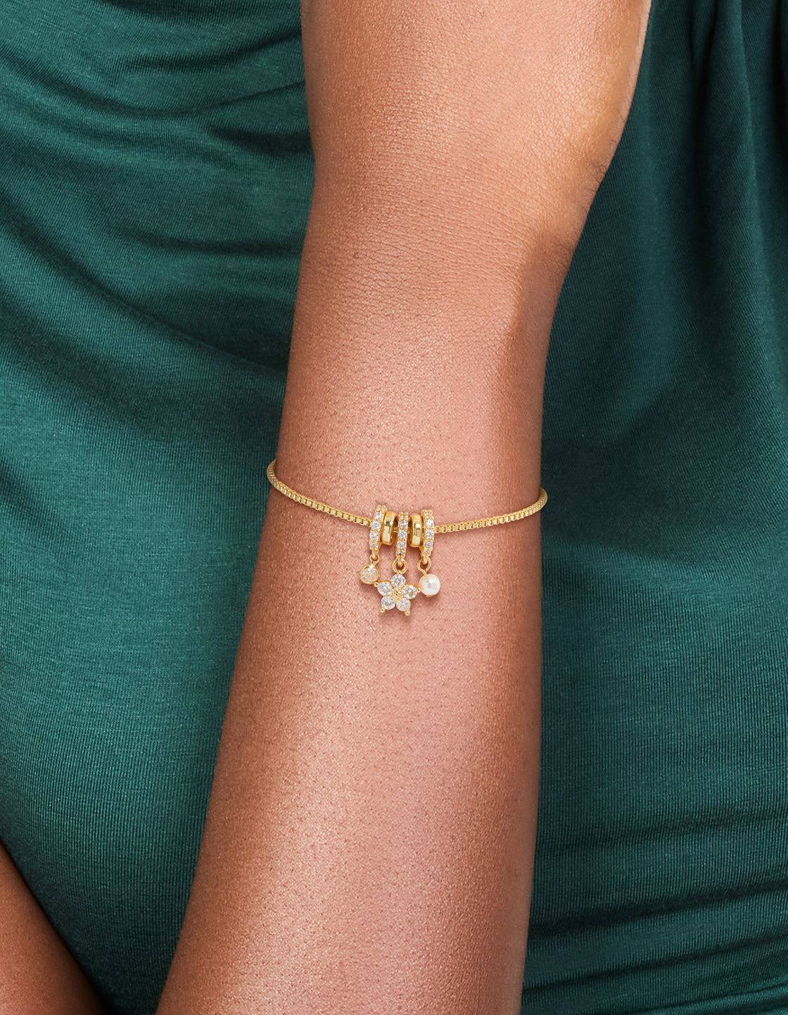 Elegant gold plated toggle bracelet with floral cubic zirconia charms and pearl rondell accents on wrist view