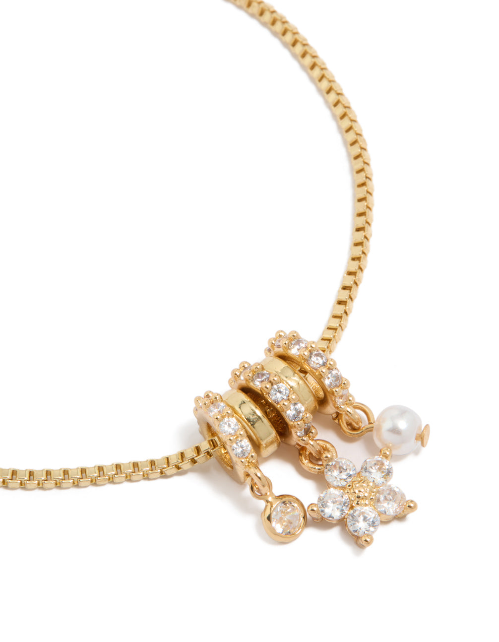 Delicate gold plated toggle bracelet with floral cubic zirconia charms and pearl rondell accents close up view