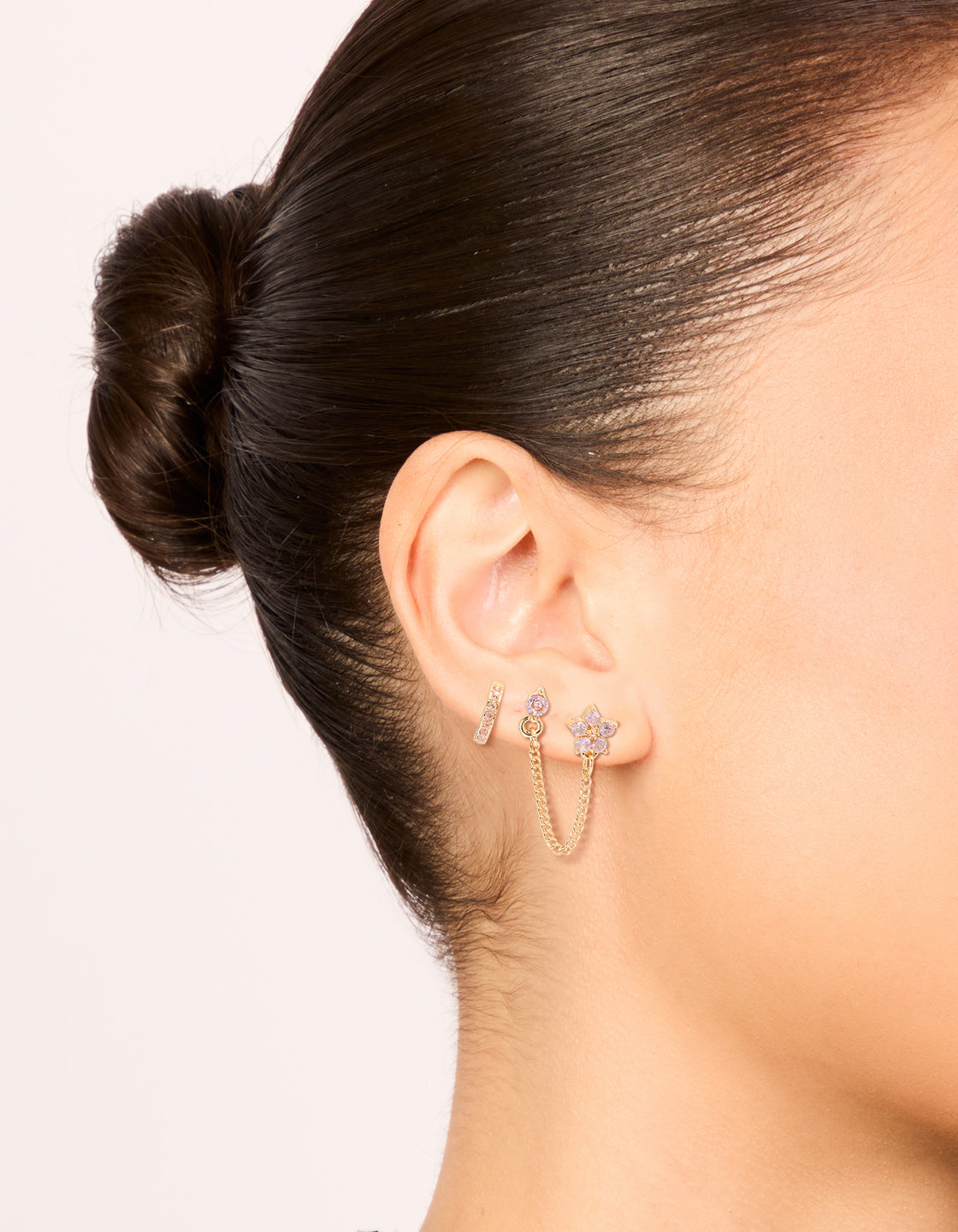 Showcasing floral chain stud and huggie earrings with pink cubic zirconia crystals in gold on ear view