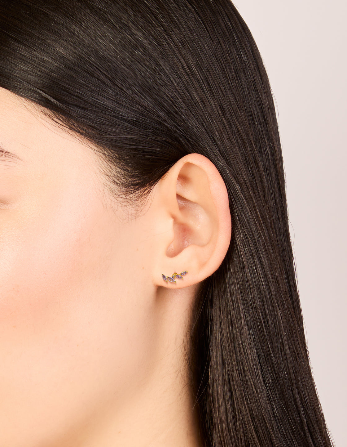 Showcasing gold plated surgical steel purple cubic zirconia crawler studs with flat back closure on ear view