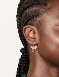 Featuring pink dragonfly gold huggie hoop earrings with animal charm, wings, and glitter accents on ear view - link has visual effect only