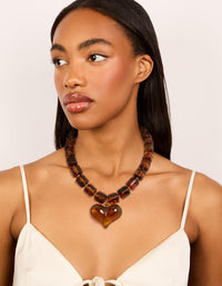 Crafted with brown square beads and a heart necklace in gold tones on model view - link has visual effect only