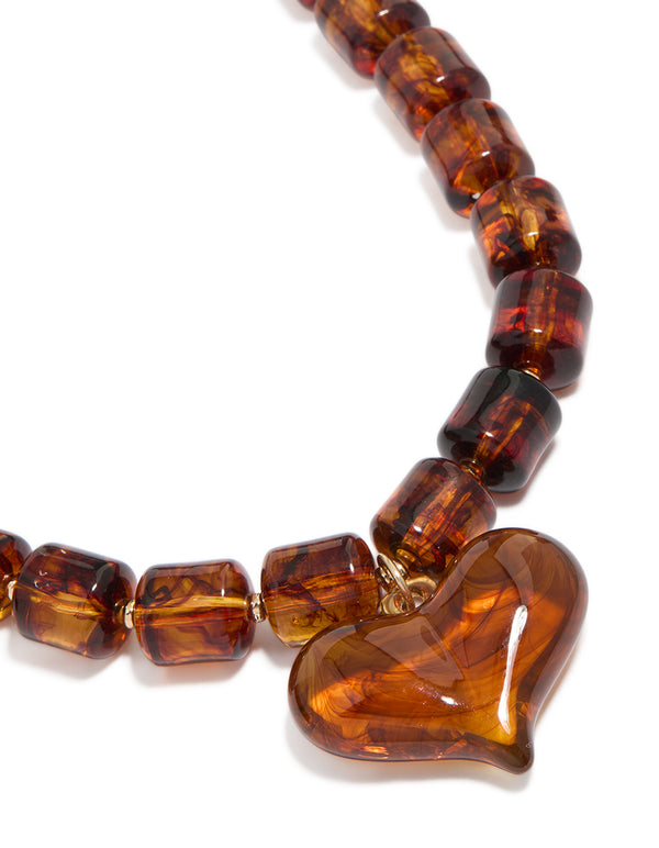 Showcasing a brown square bead and heart necklace detail in gold tones close up view