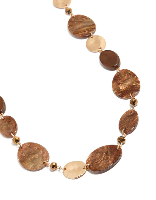 Showcasing a beaded glittery gold statement necklace close up view