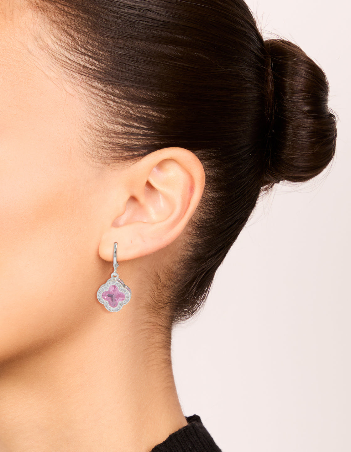 Showcasing silver pink cubic zirconia floral huggie earrings on ear view