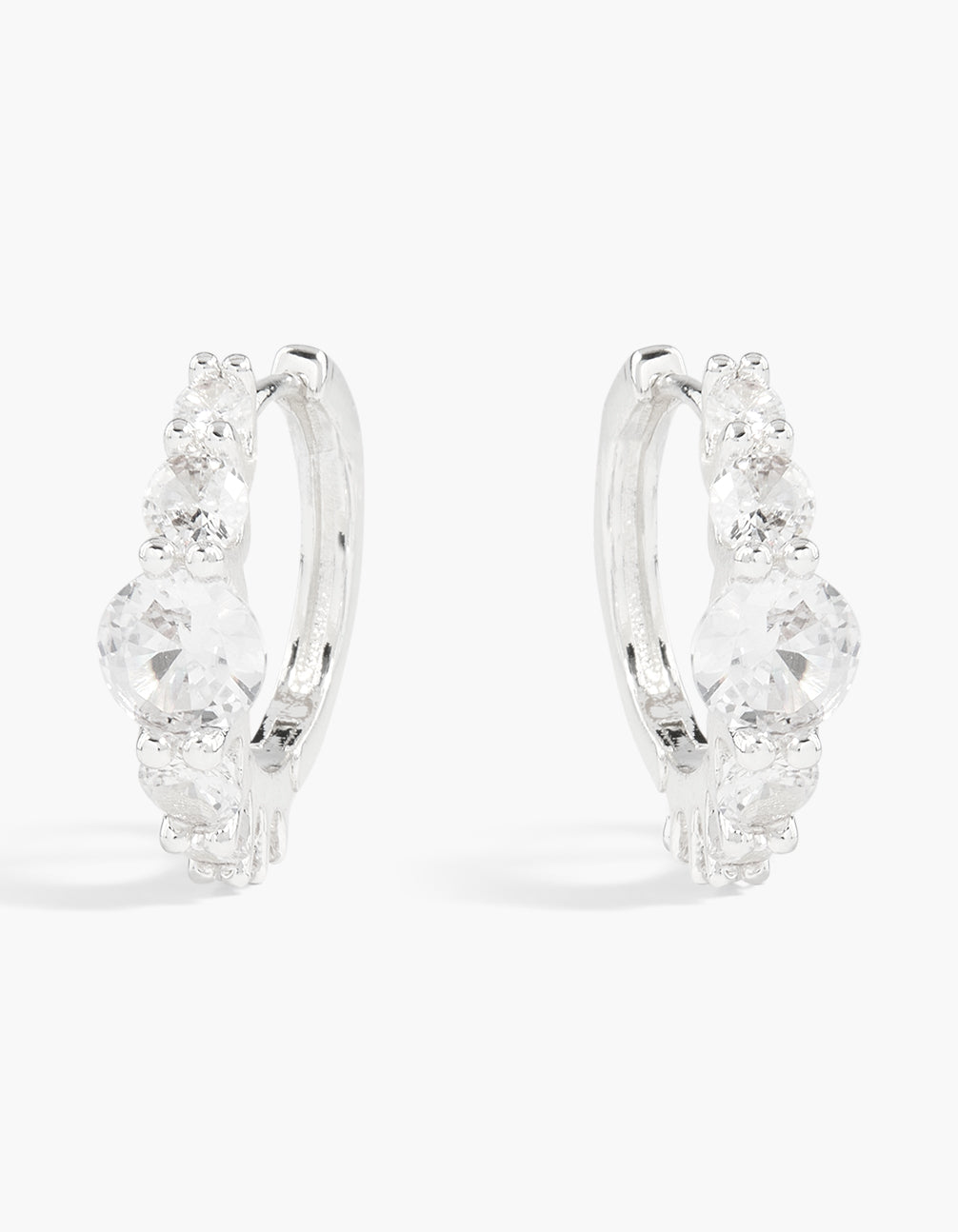 Crafted from silver plated material, these graduating round cubic zirconia hoop earrings feature a polished finish with sparkling stones front view